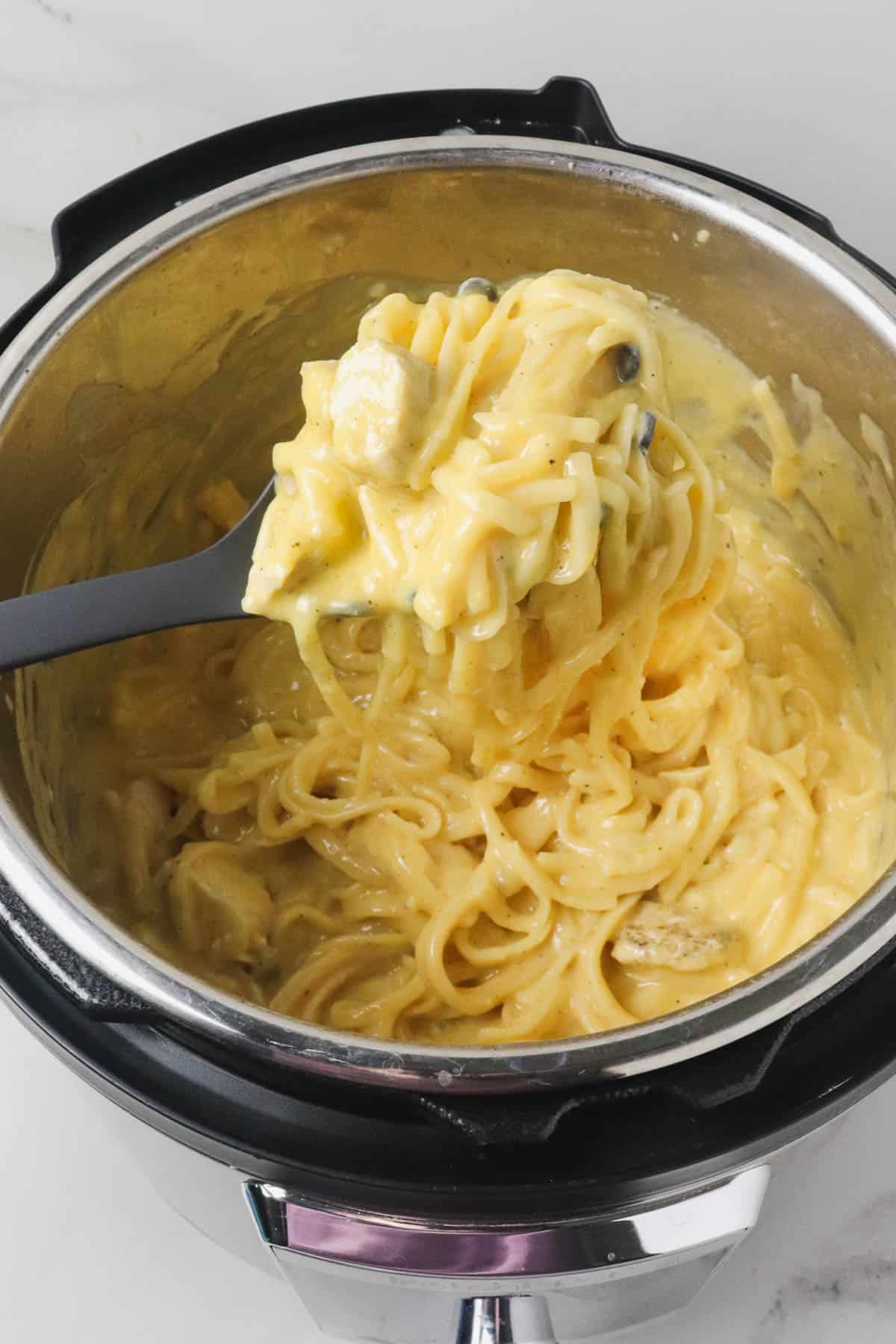 scooping a serving cheesy chicken spaghetti from the instant pot