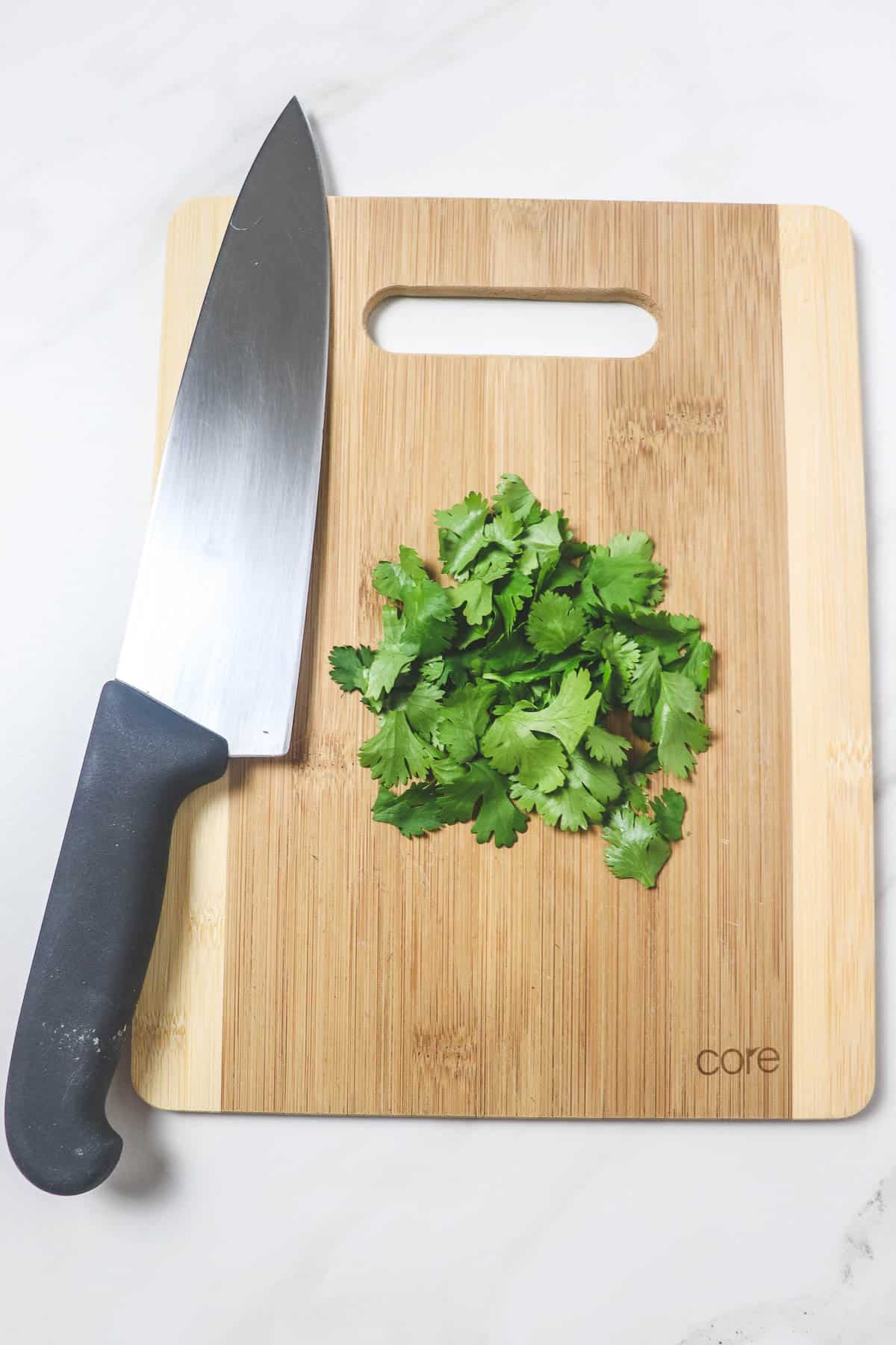 chopping fresh cilantro on wood cutting board with chef knife