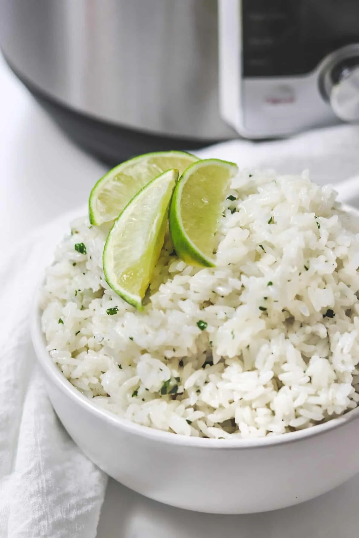 bowl of cilantro lime rice with lime wedges in front of instant pot