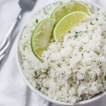cilantro lime rice in bowl with lime wedges on top