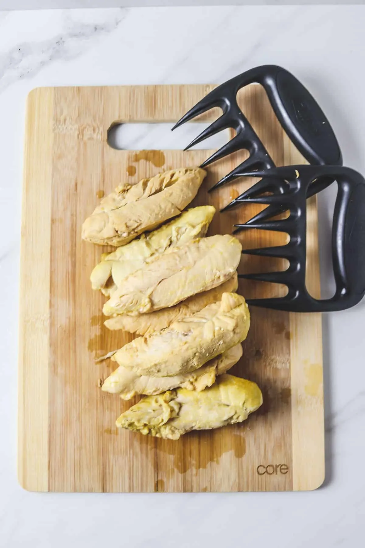 cooked chicken tenders on a cutting board ready to shred