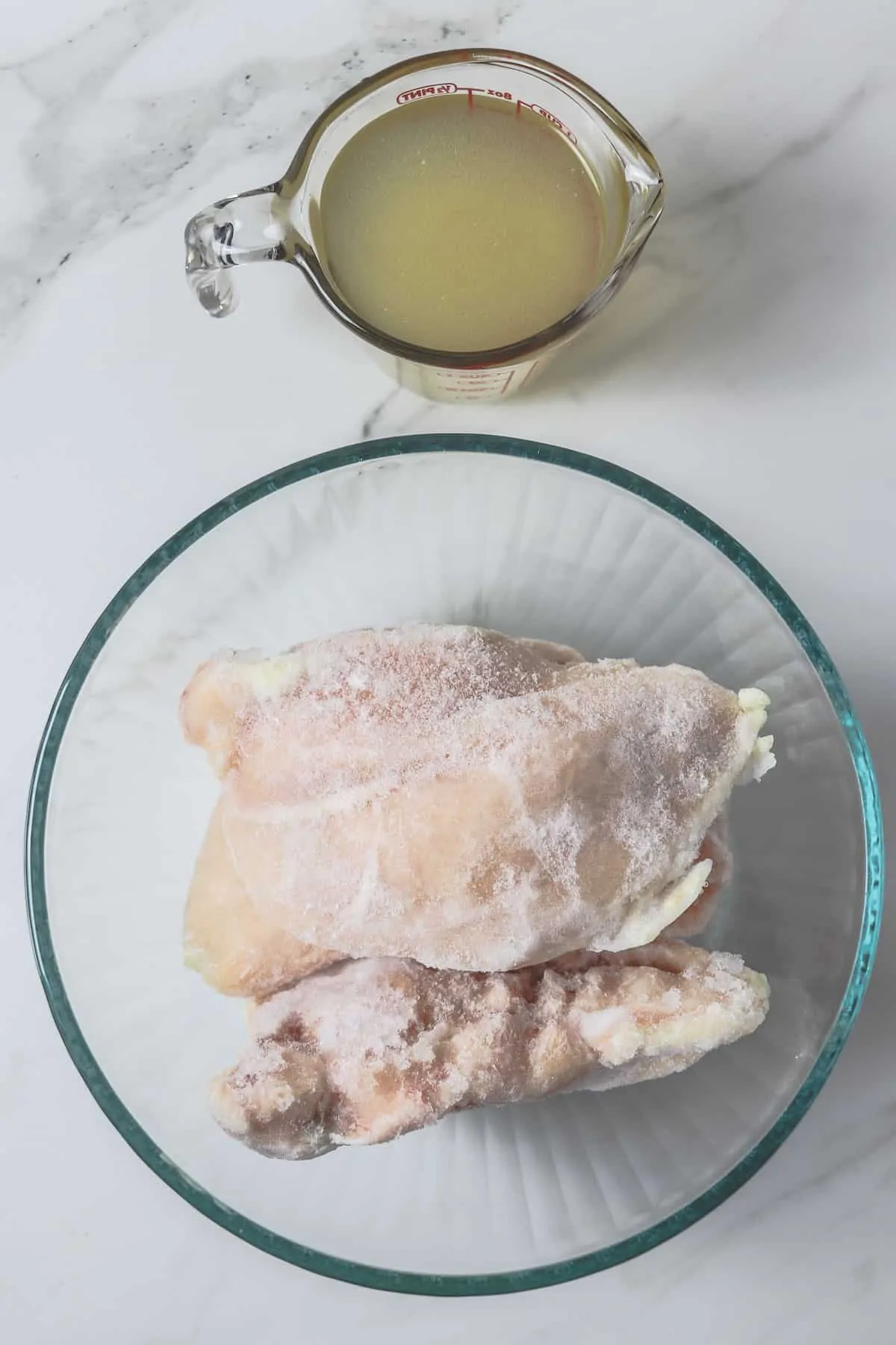 frozen chicken breasts in a bowl with one cup of chicken broth