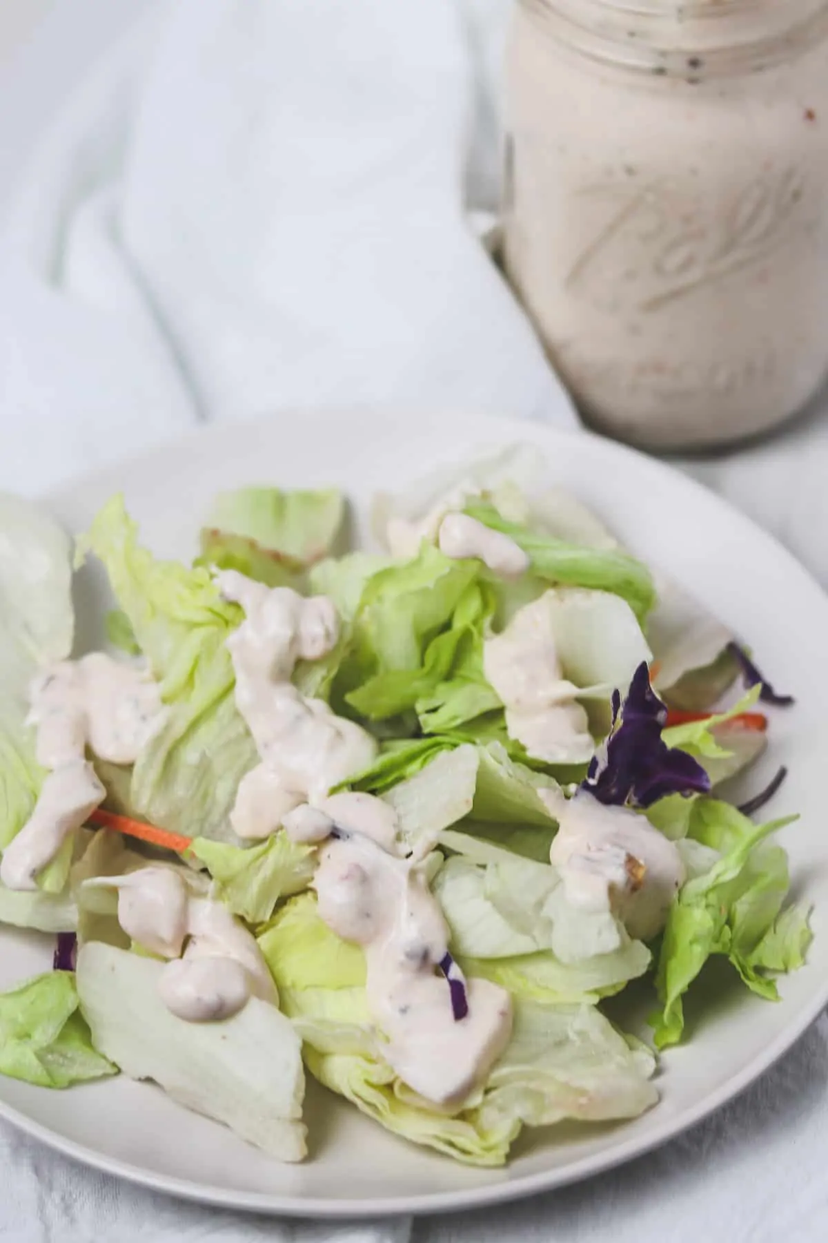 side salad topped with lighter salsa ranch dressing on a white plate