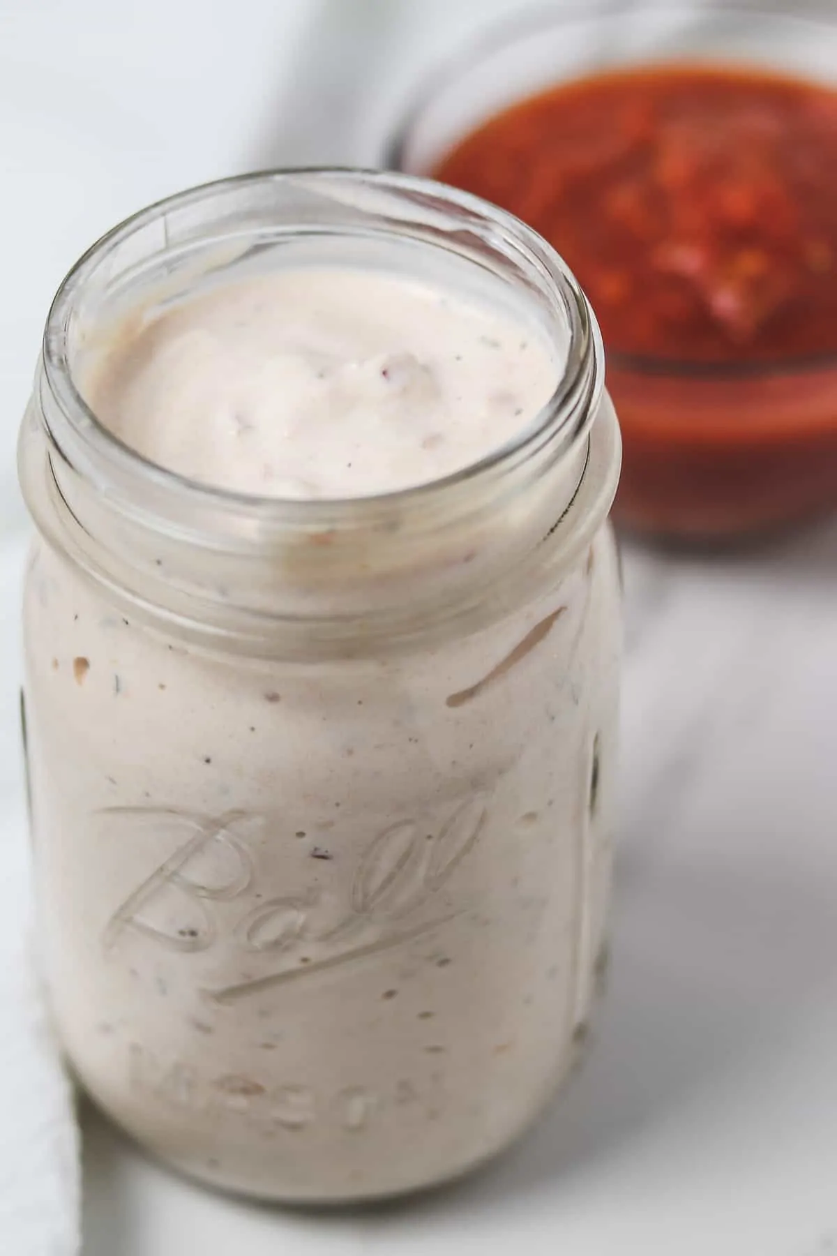 mason jar of skinny salsa ranch dip with a bowl of salsa in the background