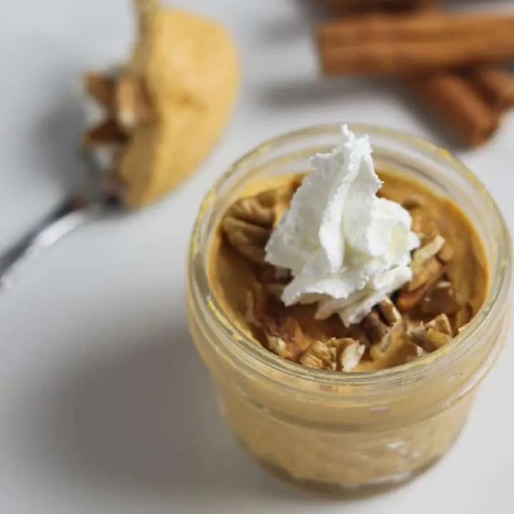 pumpkin fluff dessert in a glass jar topped with whipped cream and pecans
