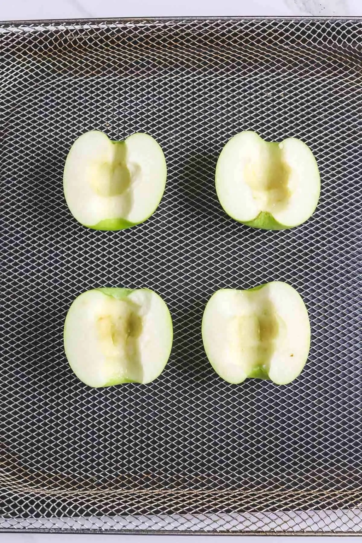 uncooked apple halves in air fryer basket