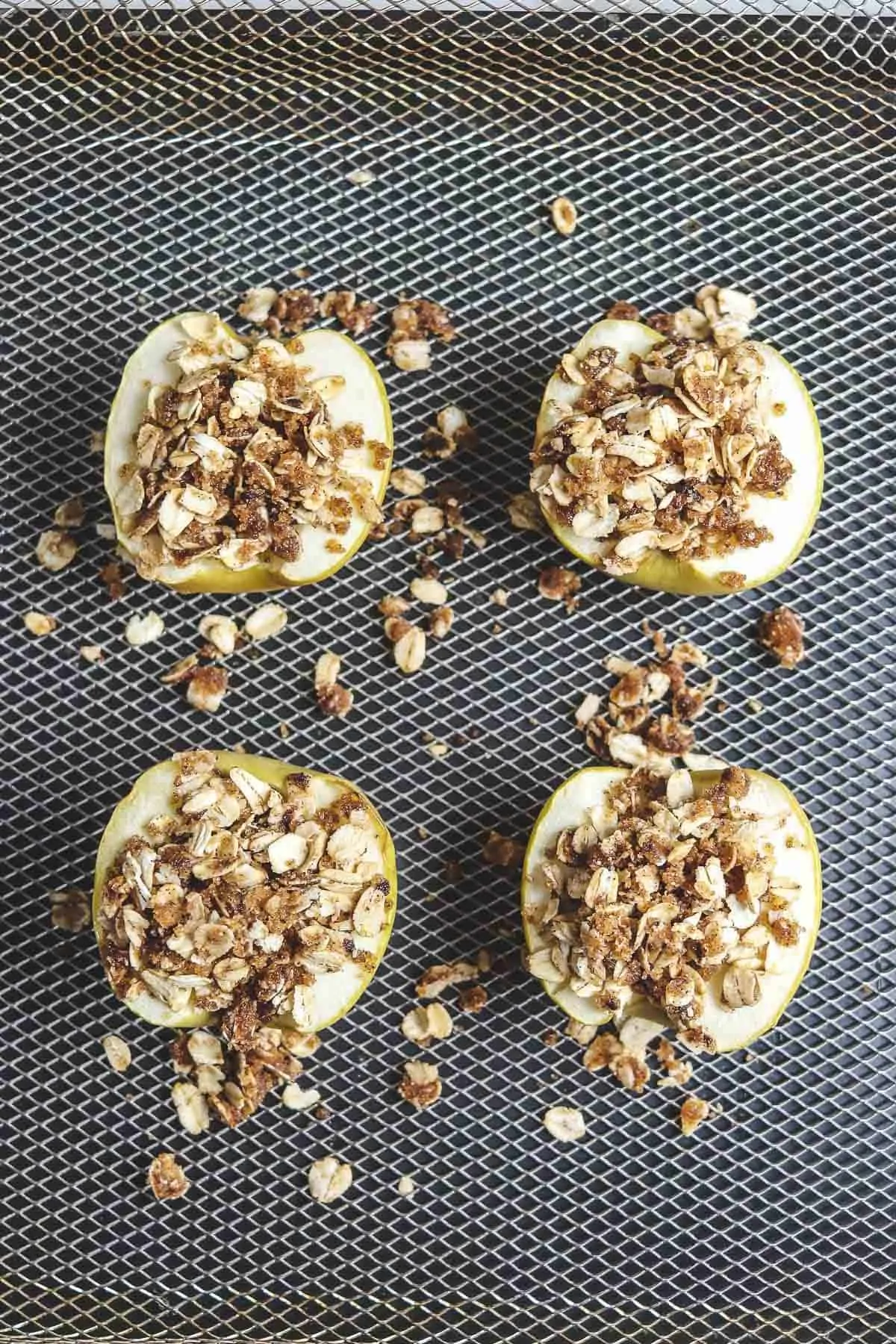 apple halves topped with oat topping in air fryer basket