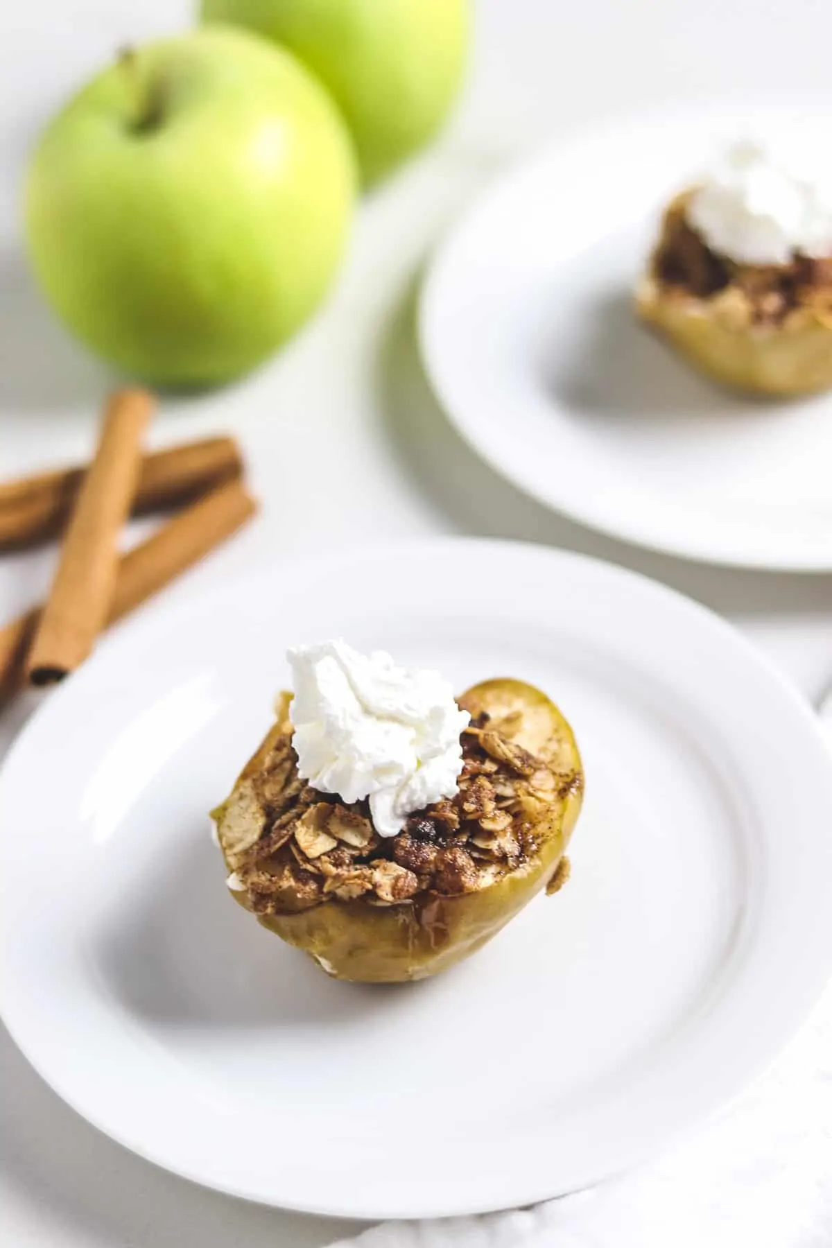 air fryer baked apple on white plate topped with whipped cream