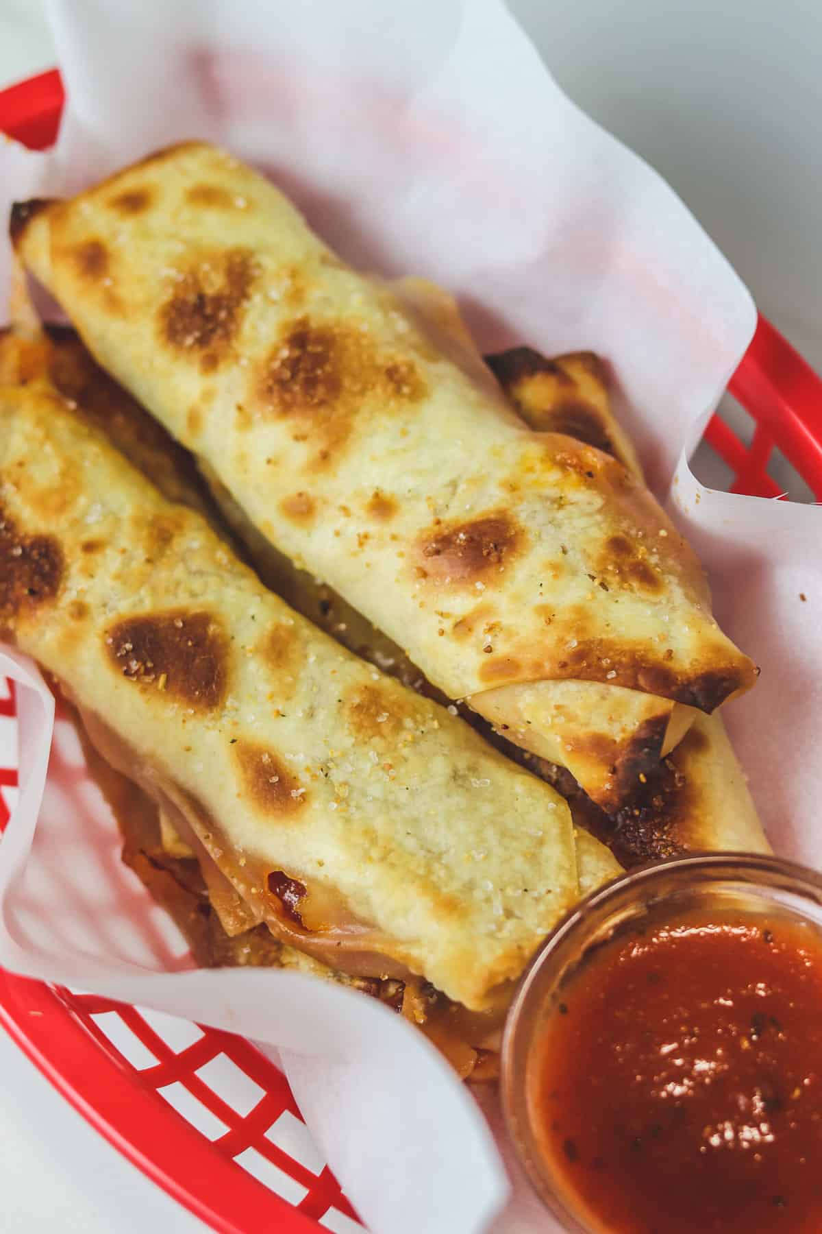 air fried pizza rolls in red basket with pizza sauce
