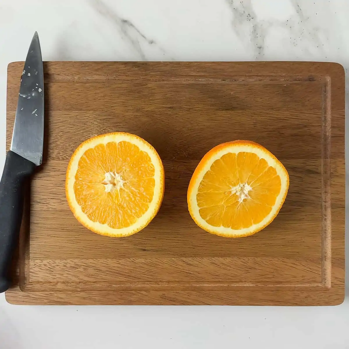 navel oranges sliced in half on wood cutting board