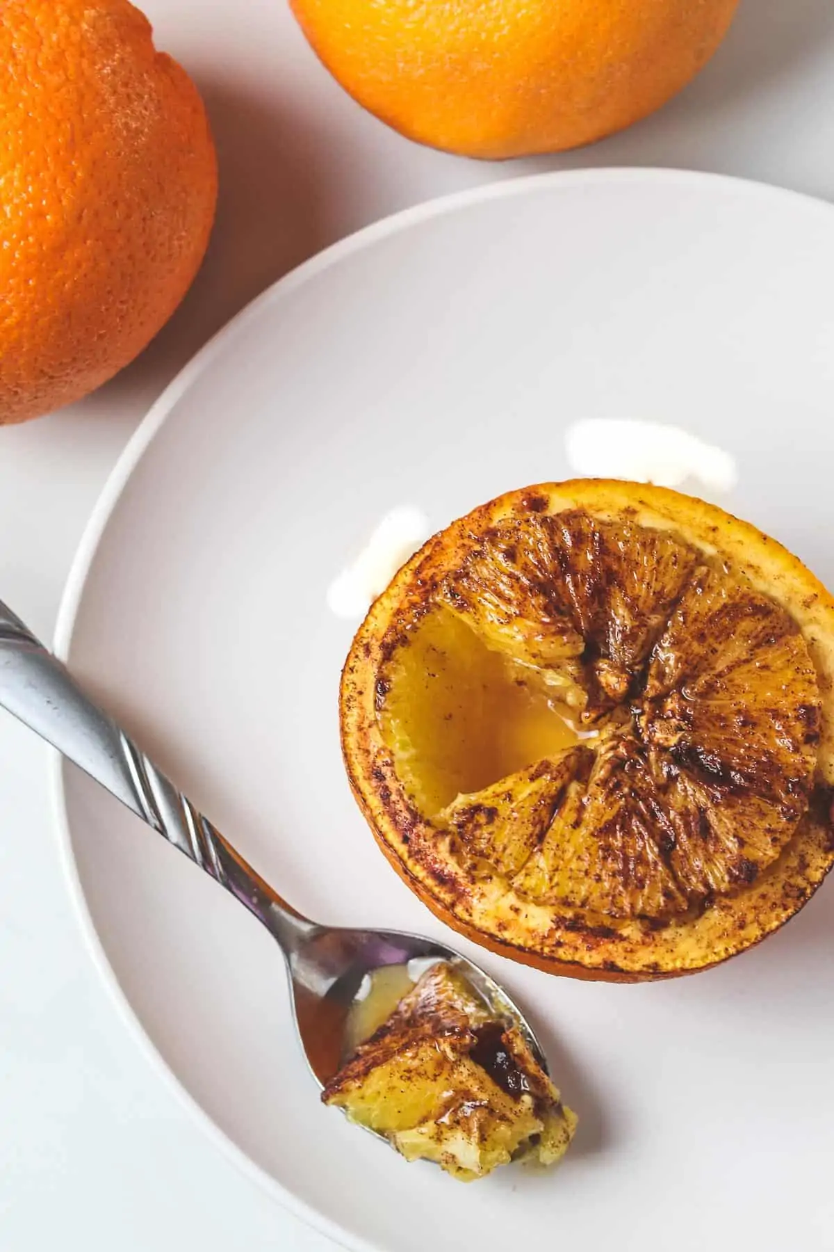 baked orange on a white plate with a bite in a spoon