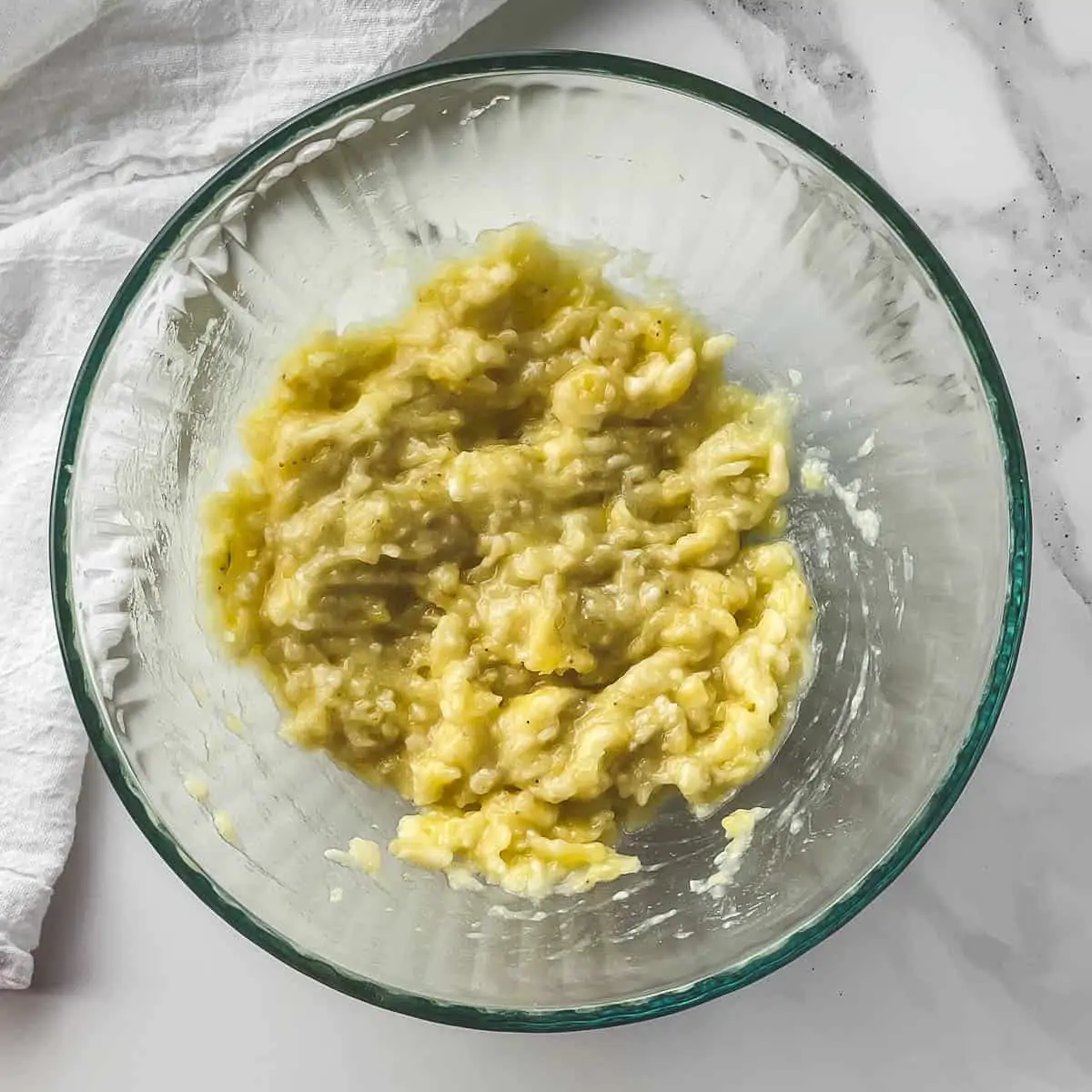 mashed bananas in a glass mixing bowl