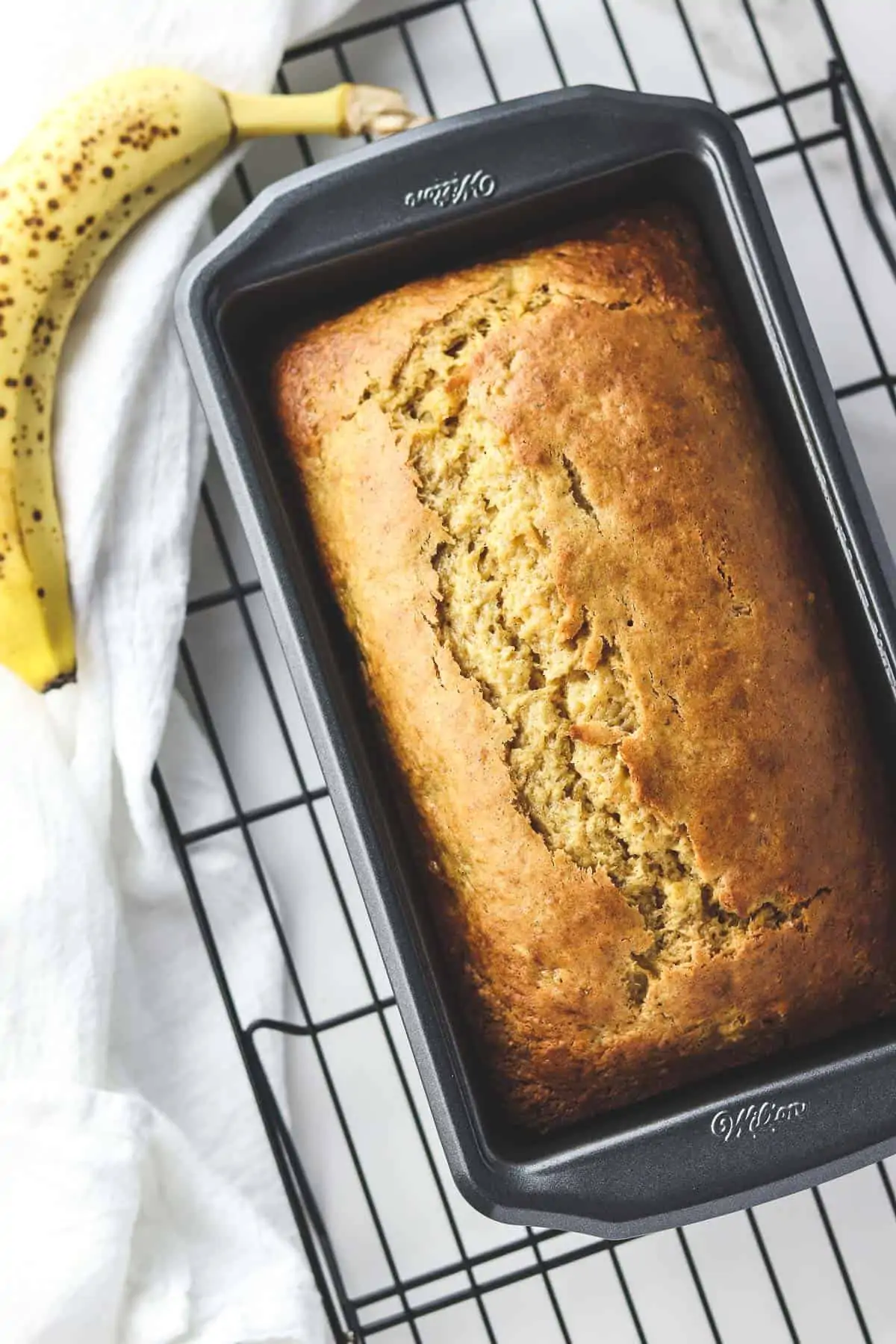 healthy banana bread in a loaf pan with a ripe banana
