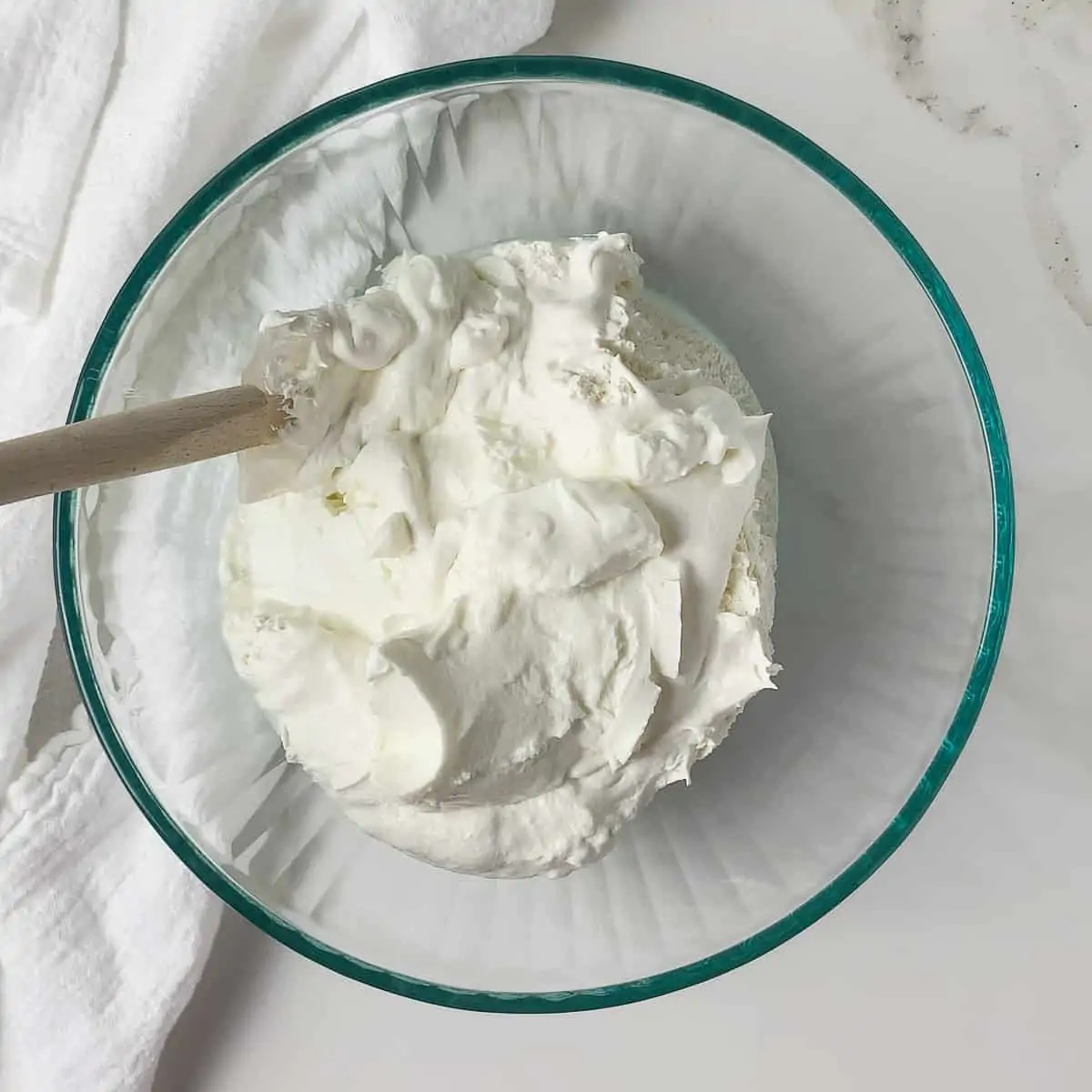 yogurt and cool whip in a glass mixing bowl