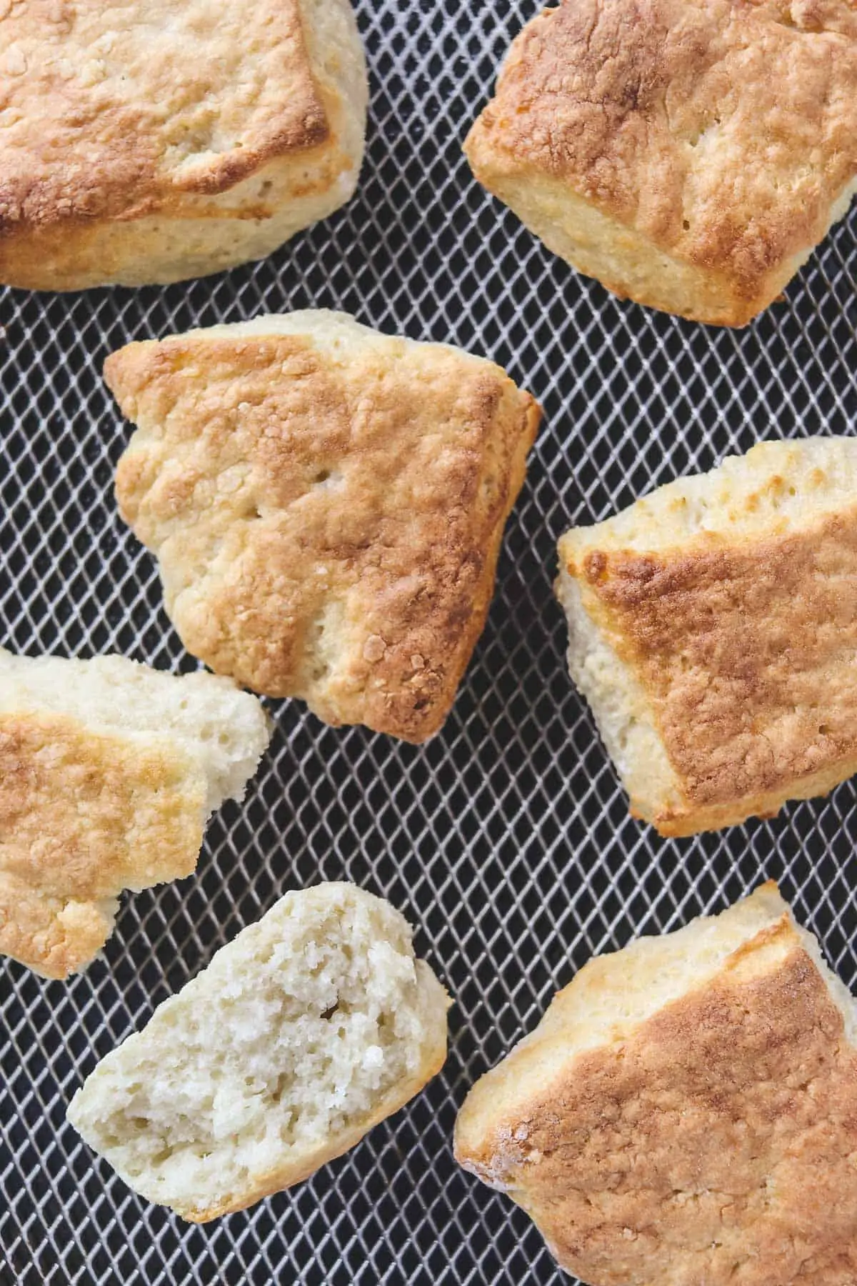 cooked biscuits in the air fryer basket with one torn apart