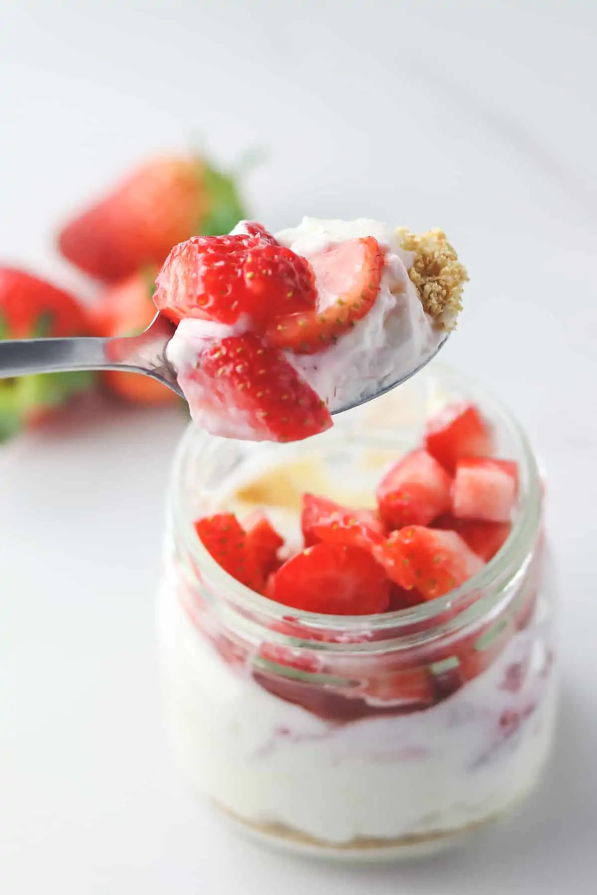 taking a bite of cheesecake topped with strawberries