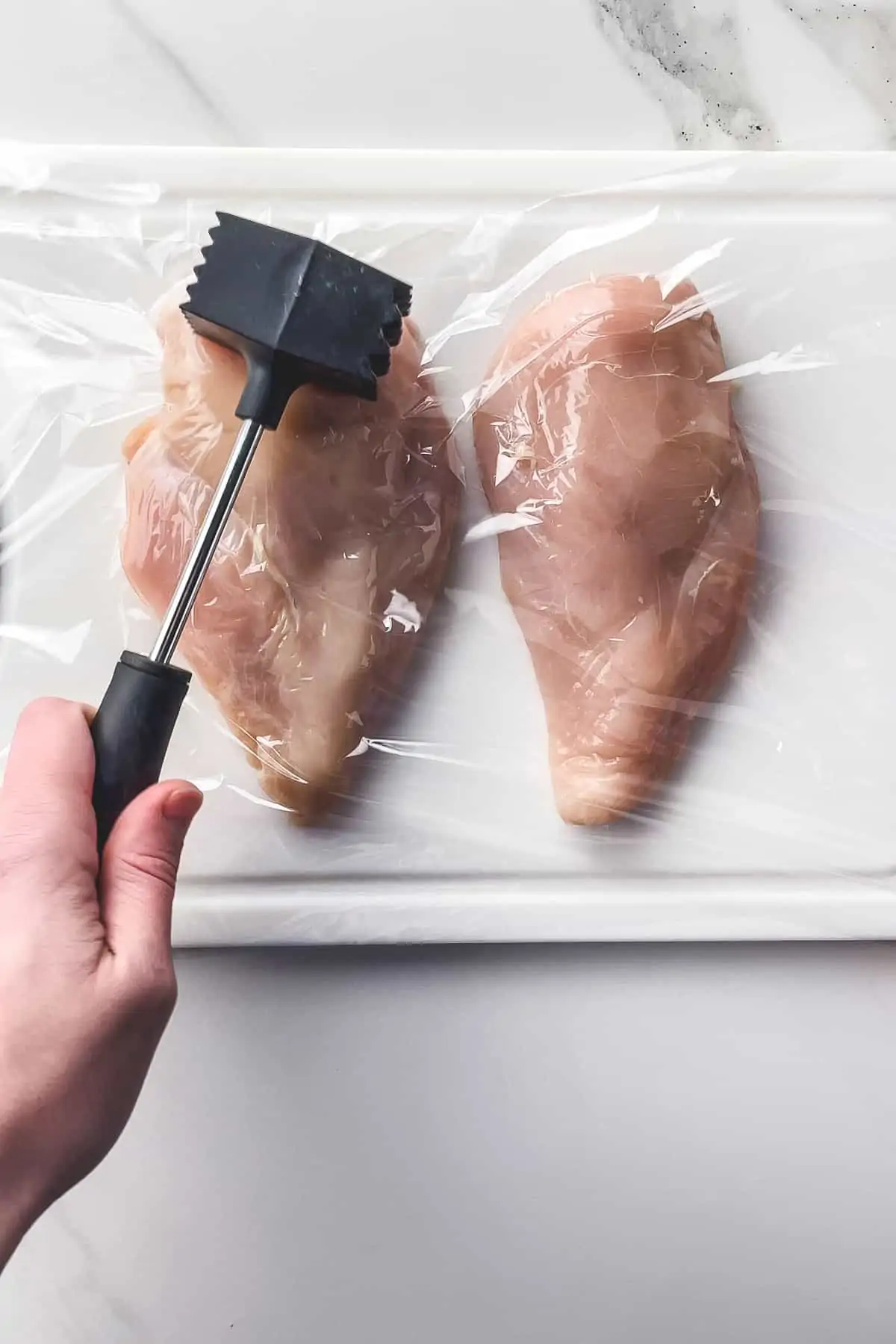 pounding chicken breasts on a cutting board