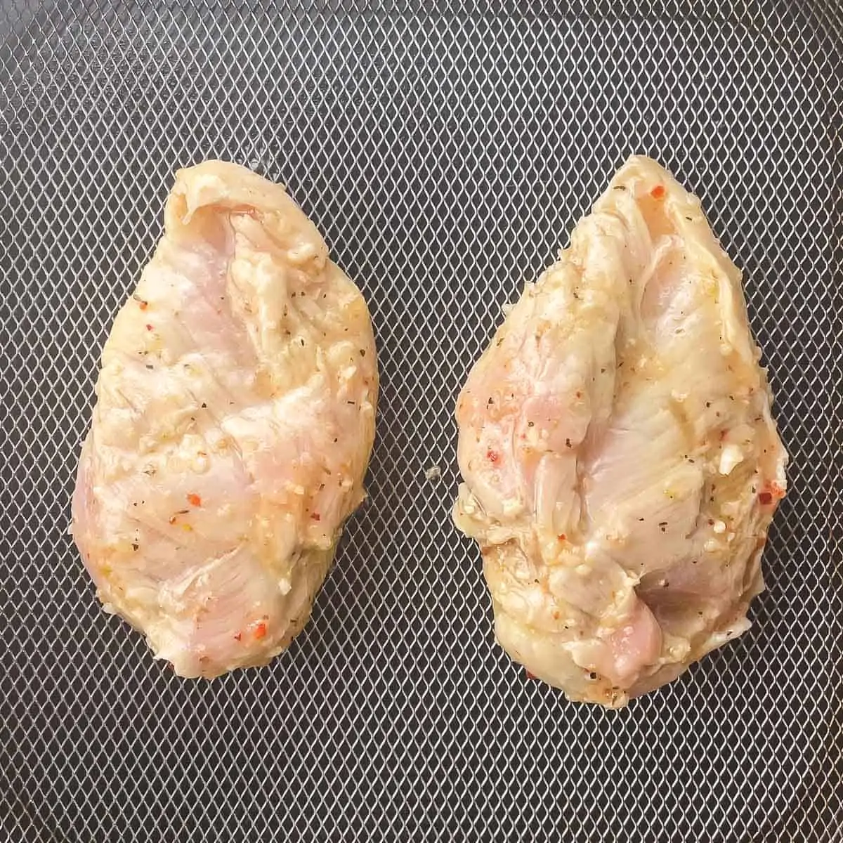 raw chicken breasts in air fryer basket