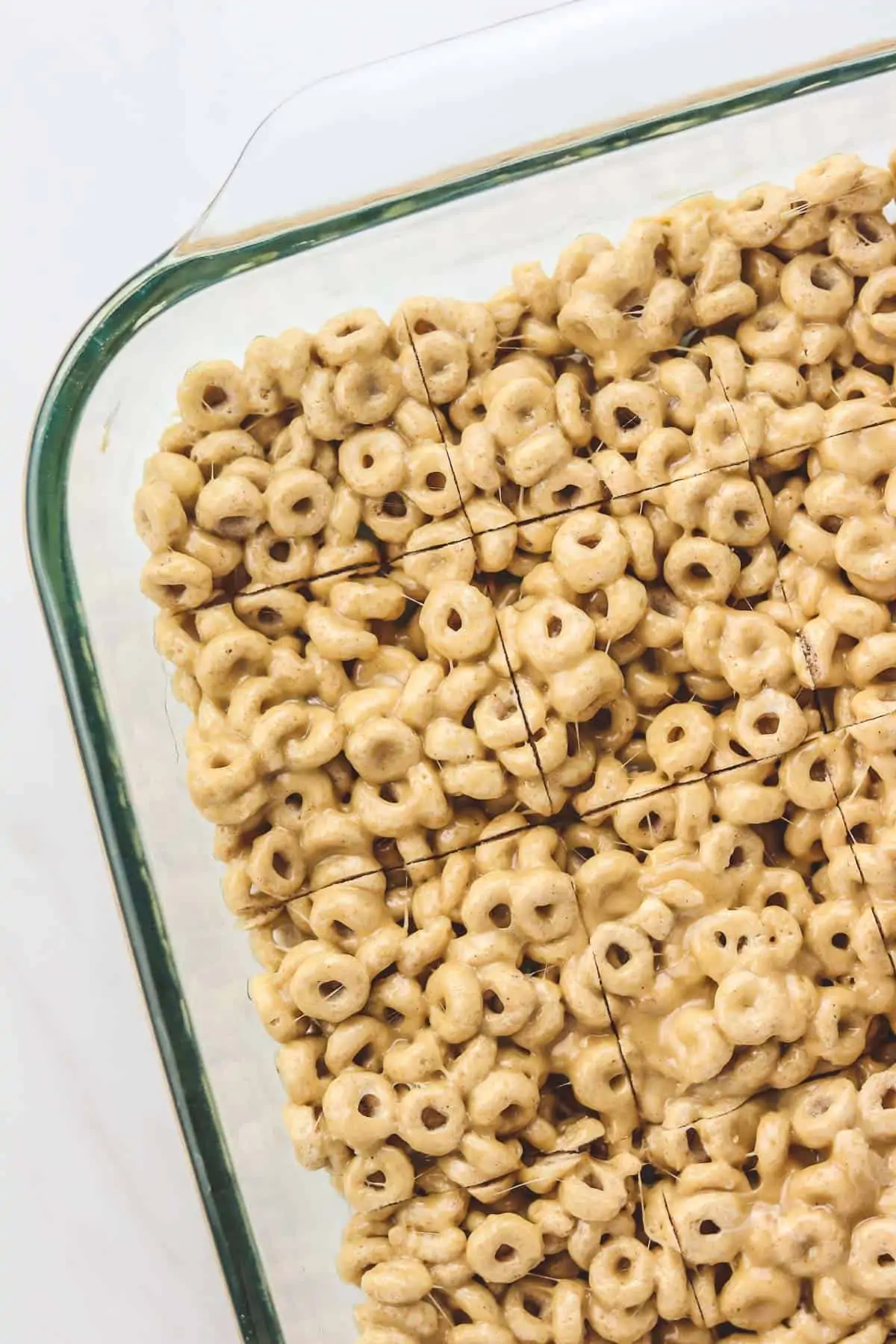 cut peanut butter cheerio bars in a glass baking pan