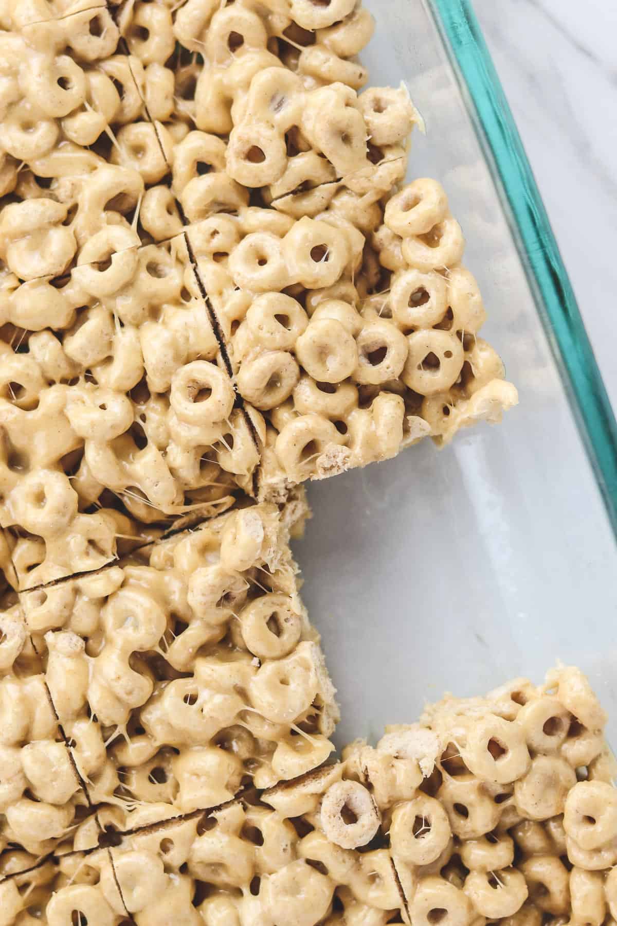 peanut butter cheerio bars in glass pan with one removed