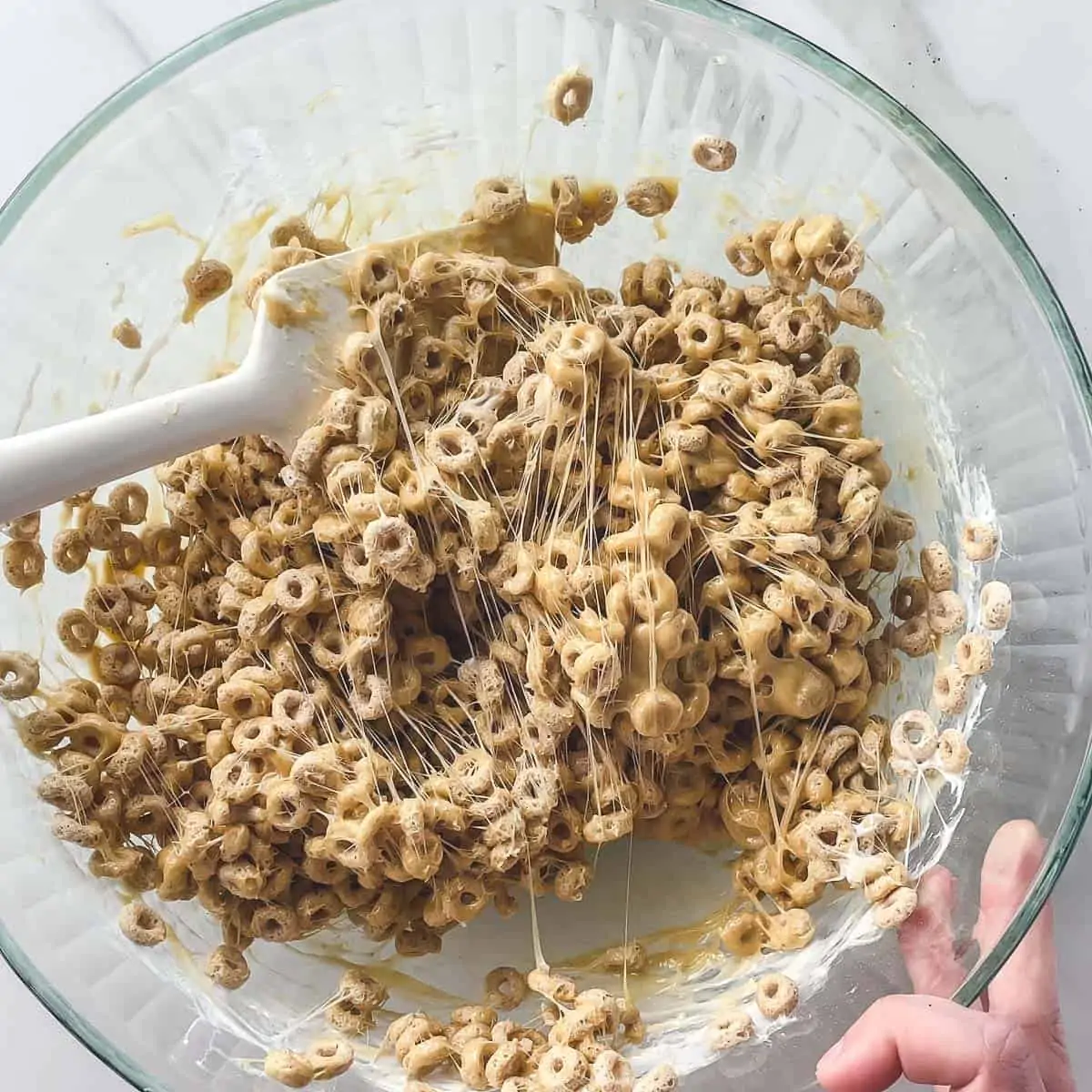 peanut butter, marshmallow, and cheerio mixture in mixing bowl