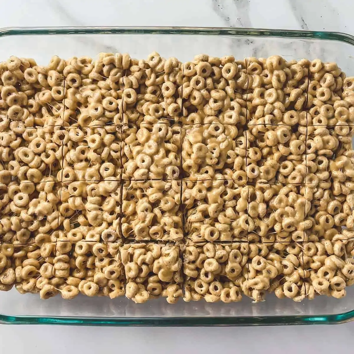 cheerio bars cut into a grid in a glass pan
