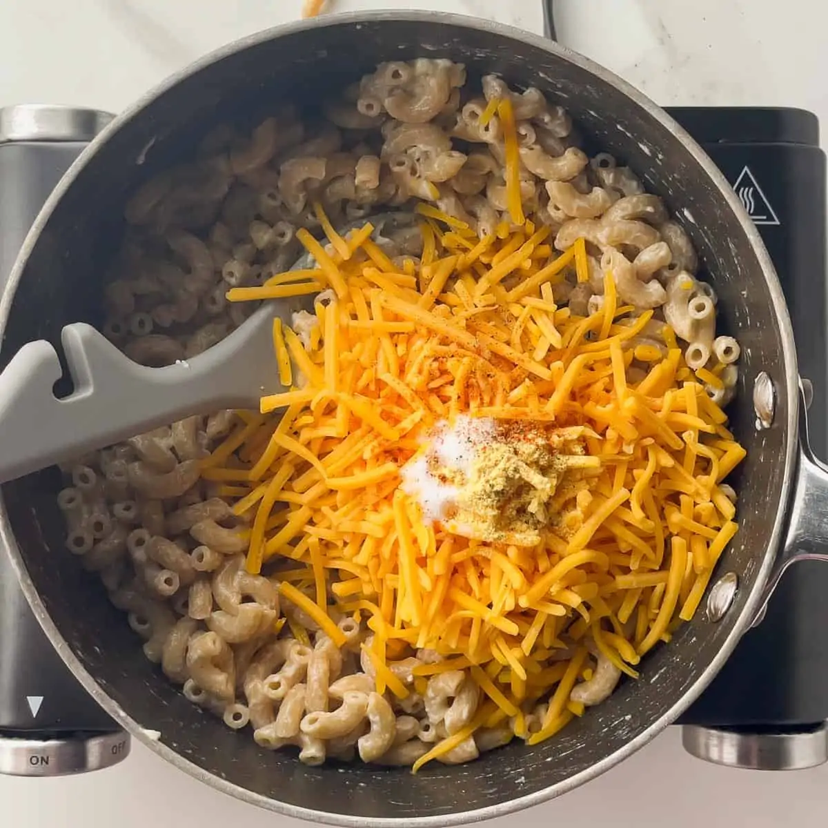 ingredients for cheese sauce tossed into the pot of noodles