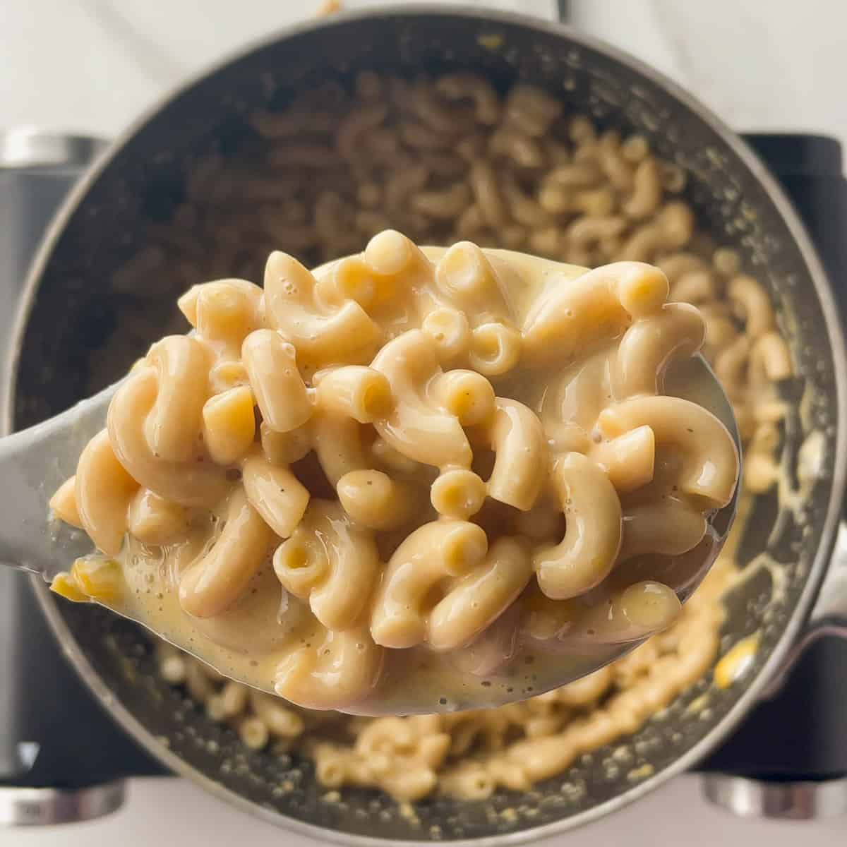 scooping a spoonful of mac and cheese out of the pot