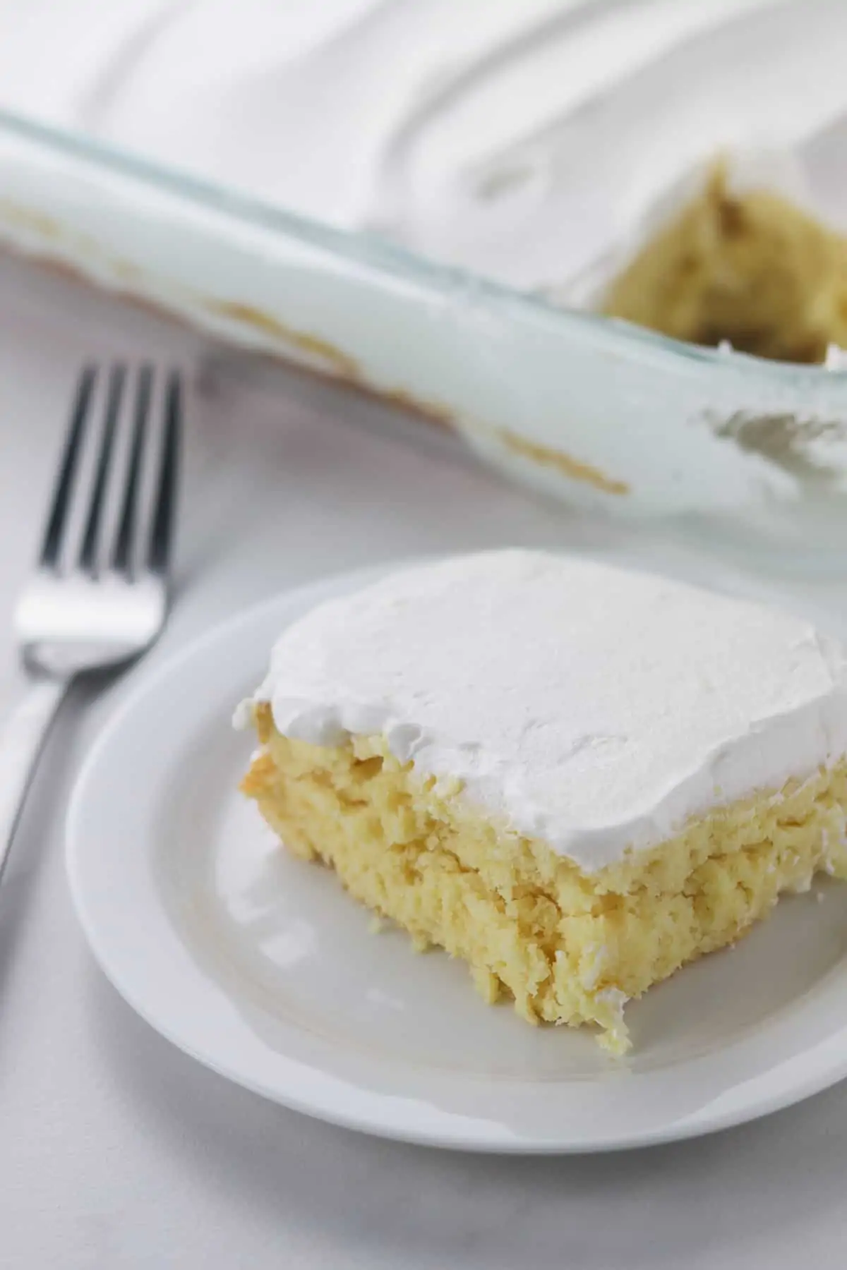 a piece of light yogurt cake on a white plate with a fork