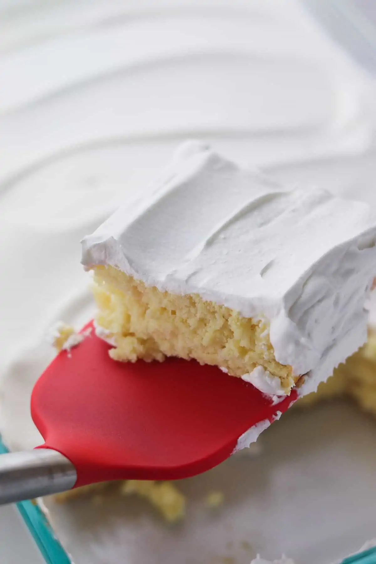 removing a slice of yellow cake topped with cool whip