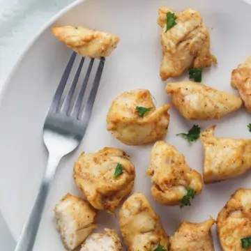 plate of rotisserie chicken bites with one piece on fork