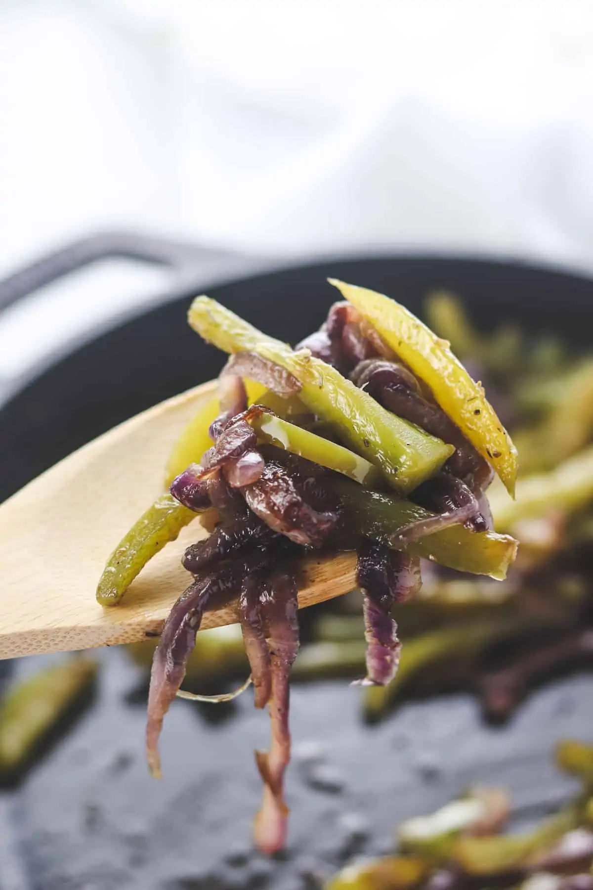 taking a spoonful of peppers and onions with a wooden spoon