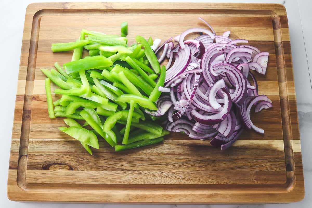 sliced green bell peppers and red onion on a cutting board