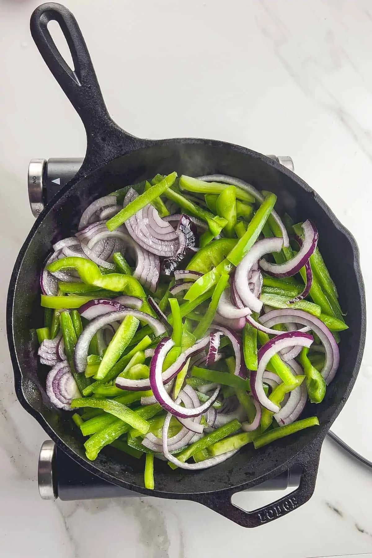 uncooked bell pepper and onion slices in a cast iron skillet