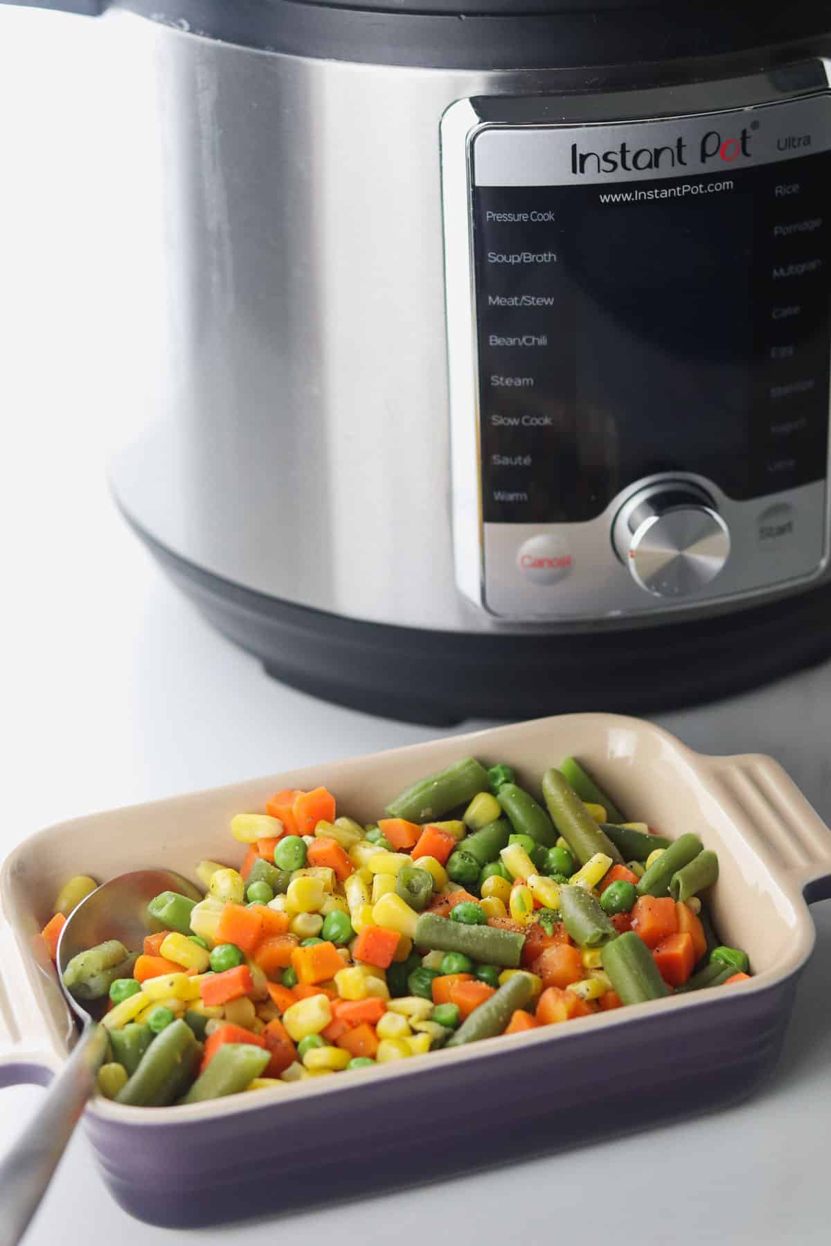 serving dish of mixed vegetables in front of the instant pot
